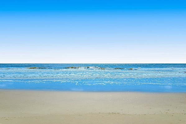 Ein Strand mit klarem, blauem Wasser und sandigem Ufer.