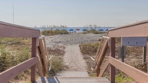 A wooden pathway leading to beach umbrellas and a view of the ocean. - Oceanfront Villa with Ocean Views, Shared Pool/Hot Tub, and Nearby Beach Access (Hilton Head)
