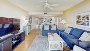 A living room with a TV, sofa, coffee table, and a ceiling fan. - Oceanfront Villa with Ocean Views, Shared Pool/Hot Tub, and Nearby Beach Access (Hilton Head)