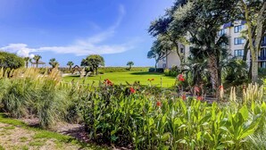 Un rigoglioso giardino con un campo da golf, un gazebo e un edificio a più piani con balconi.
