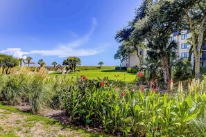 A lush garden with a golf course, a gazebo, and a multi-story building with balconies. - Calming Condo Getaway with Shared Pool, Hot Tub, and Tennis Courts (Hilton Head)