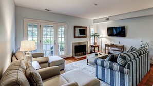 A living room with a sofa, armchairs, a coffee table, a fireplace, a television, and a large window. - Intimate, Yet Spacious Villa with Shared Pool and Tennis - Walk to the Beach (Hilton Head)