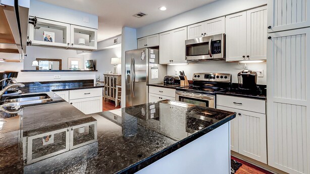 A modern kitchen with white cabinetry, stainless steel appliances, and a black granite countertop. - Intimate, Yet Spacious Villa with Shared Pool and Tennis - Walk to the Beach (Hilton Head)
