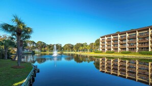Un hotel con una piscina a riflesso, una fontana e una palma.
