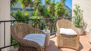A balcony with wicker chairs, a potted plant, and a railing. - Coastal Condo Steps to Beach & Downtown (San Clemente)