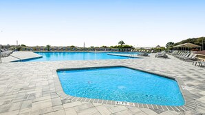 Una piscina con varias pistas, tumbonas y un solárium con baldosas.