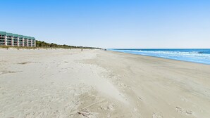 Una playa con un edificio de hotel al fondo.