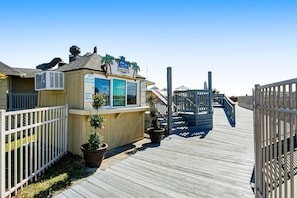 A wooden boardwalk leading to a building with a sign reading 'Jamaica Market.' - 3rd-floor snowbird-friendly condo with pool, tennis, volleyball, gym, & balcony (Hilton Head)