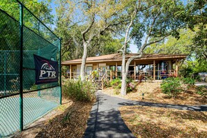 A building with a covered porch, a pathway leading to it, and a chain-link fence with a sign. - 3rd-floor snowbird-friendly condo with pool, tennis, volleyball, gym, & balcony (Hilton Head)