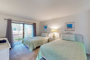 Una habitación con dos camas, un escritorio, una lámpara y vistas al exterior.