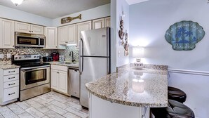 A kitchen with white cabinets, stainless steel appliances, a granite countertop, and a decorative wall sign. - Updated island Villa with two pools, tennis, & game room - walk to the beach (Hilton Head)