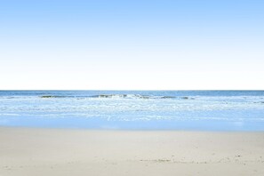 Uma praia com céu limpo e ondas calmas.