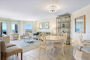 A spacious living area with a round table, chairs, a sofa, and a chandelier. - Beach-view 4th-floor condo with balcony, outdoor pool, elevator, BBQ area, W D (Hilton Head)
