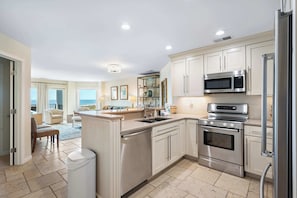 A modern kitchen with stainless steel appliances, a central island, and a view to the living area. - Beach-view 4th-floor condo with balcony, outdoor pool, elevator, BBQ area, W D (Hilton Head)