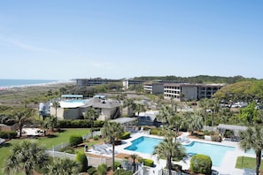 A resort with a swimming pool, palm trees, and a view of the beach. - Beach-view 4th-floor condo with balcony, outdoor pool, elevator, BBQ area, W D (Hilton Head)