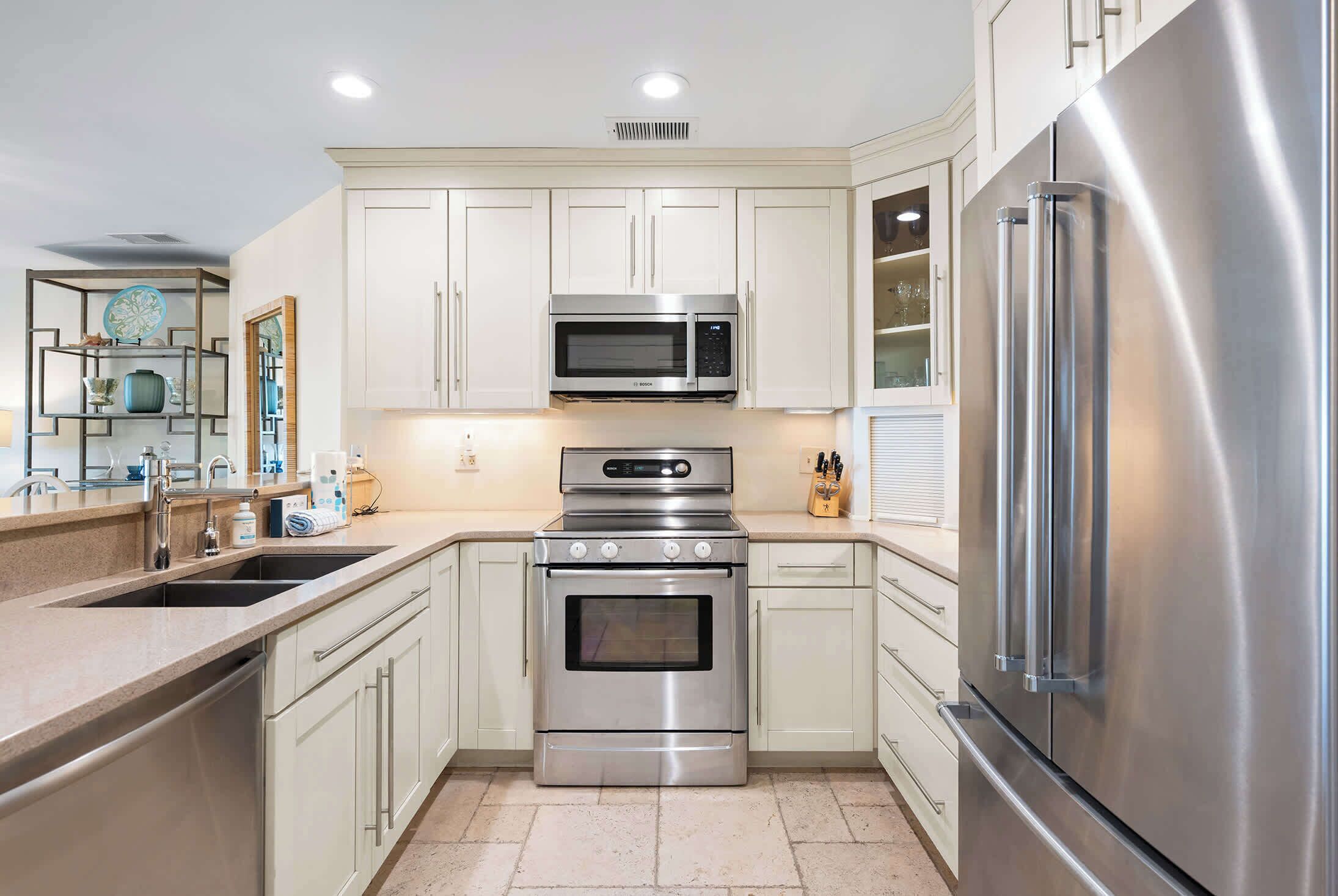 A modern kitchen with stainless steel appliances, white cabinetry, and a built-in oven.