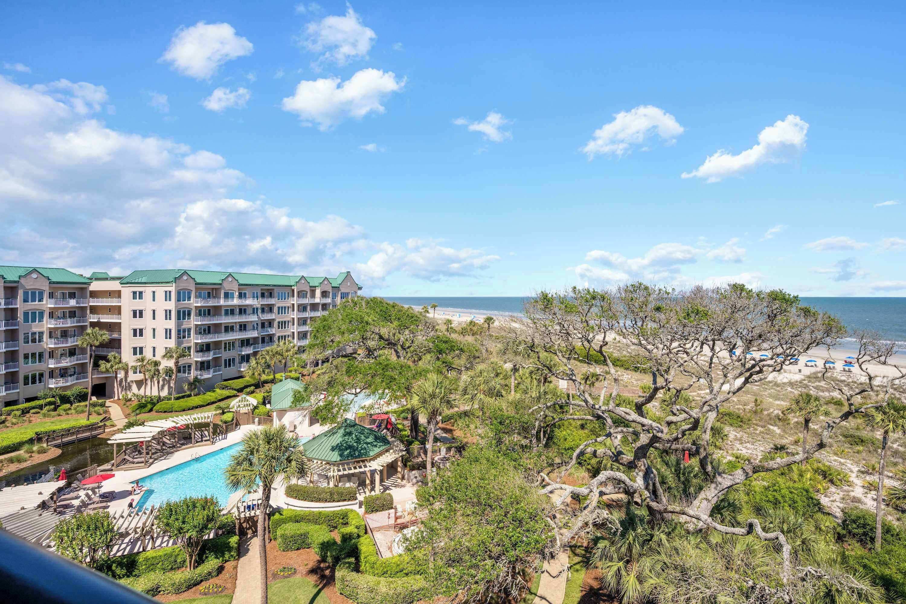 A hotel with a pool, beach view, and multiple balconies.