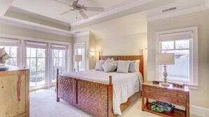 A bedroom with a bed, bedside tables, a ceiling fan, and large windows. - Two-story home with pool, balcony, deck, grill, & central AC - snowbirds welcome (Hilton Head)