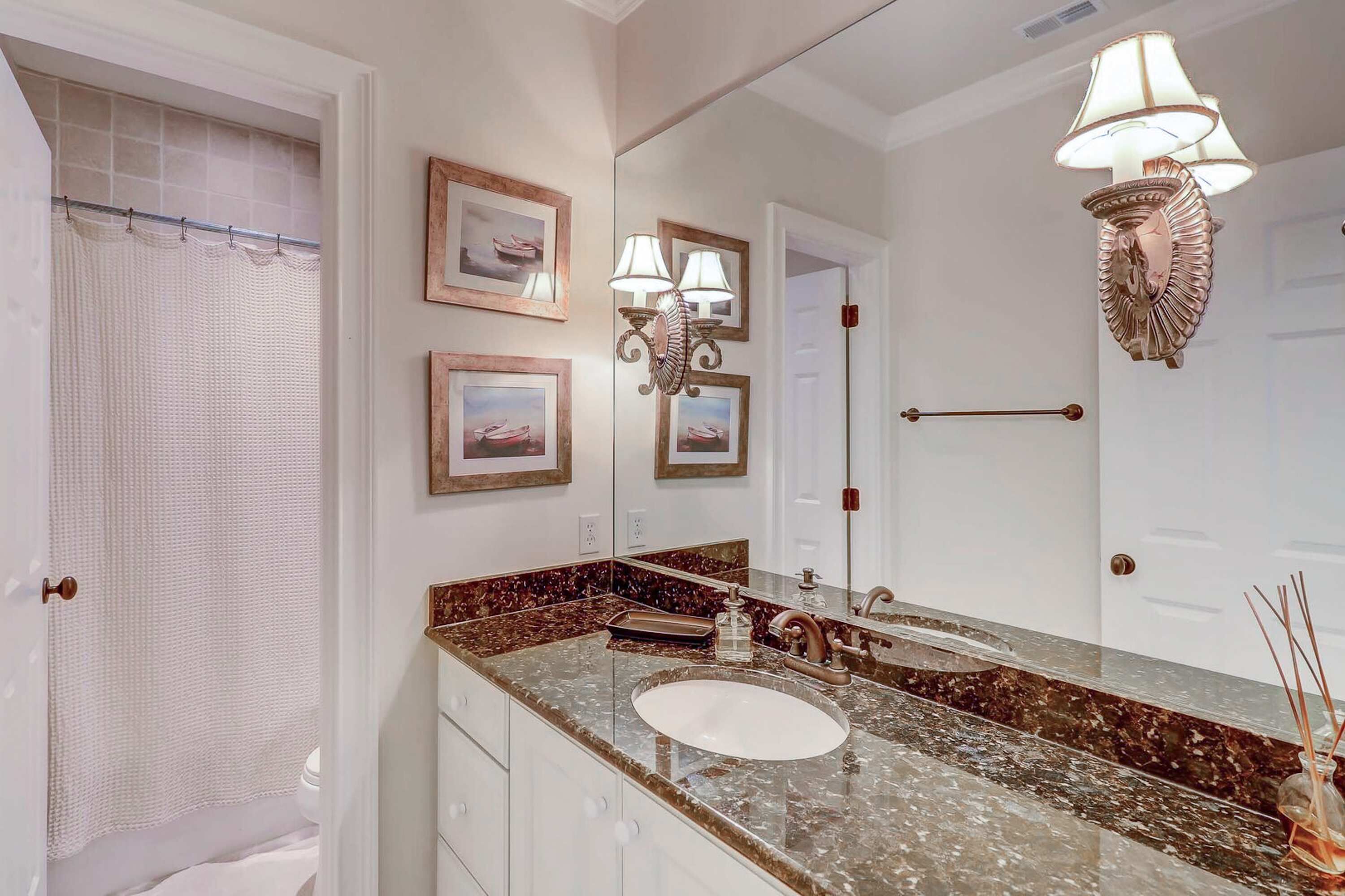 Une salle de bain avec un lavabo en marbre, des tableaux encadrés, un miroir et un porte-serviettes.