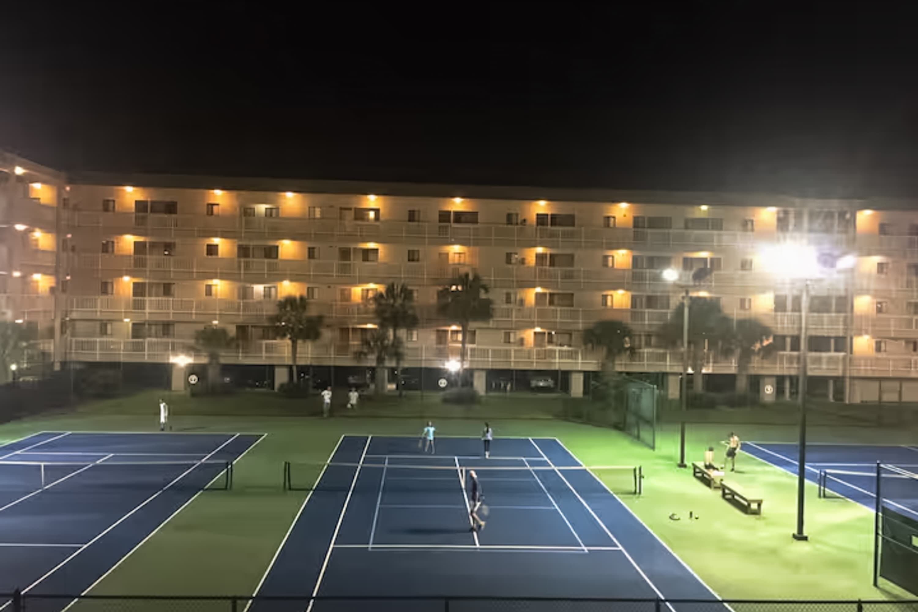 Een tennisbaan met een gebouw op de achtergrond.