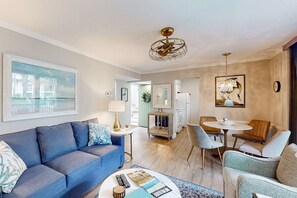 A modern living room with a sofa, coffee table, and dining area. - Charming 1st floor condo near Coligny Beach Plaza and private beach access (Hilton Head)