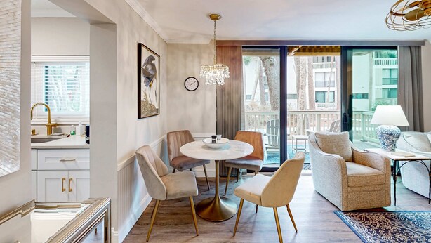 Quarto de hotel moderno com área de refeições, sofá, lustre e vista para a cidade.