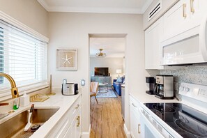 A modern kitchen with a sink, stove, and coffee maker. - Charming 1st floor condo near Coligny Beach Plaza and private beach access (Hilton Head)