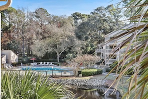 Ein Pool mit Liegestühlen, ein kleiner Teich und ein Gebäude mit einem Balkon.