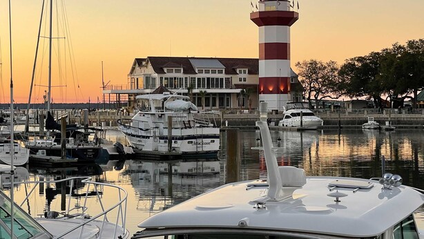A marina with boats, a lighthouse, and a building with a balcony. - Spacious lagoon-view condo with tennis, outdoor pool, beach access, balcony (Hilton Head)