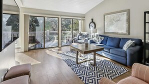 A spacious living area with a blue sofa, a patterned rug, and a wooden coffee table. - Spacious lagoon-view condo with tennis, outdoor pool, beach access, balcony (Hilton Head)