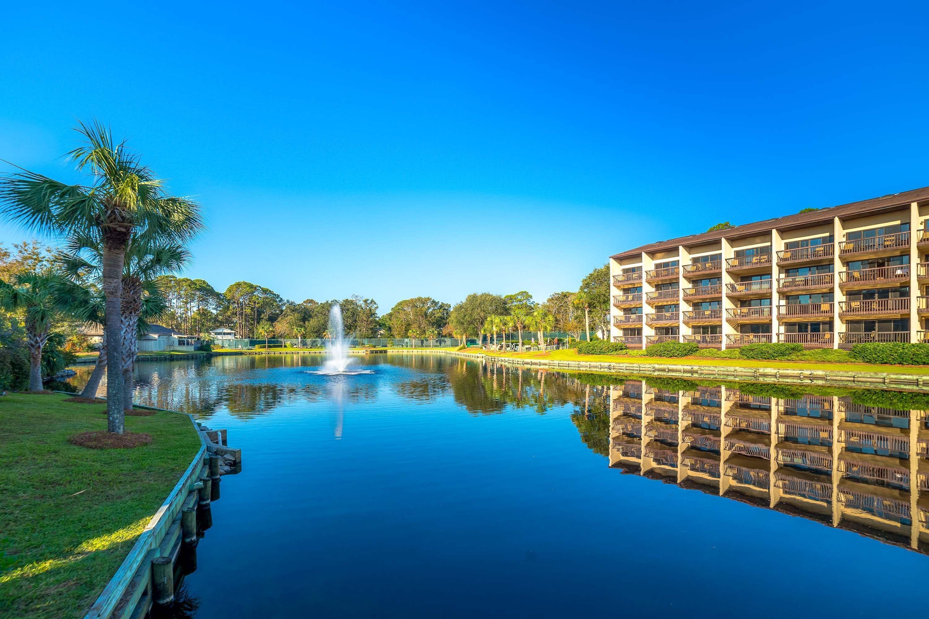 A hotel with a reflection pool, a fountain, and a palm tree.