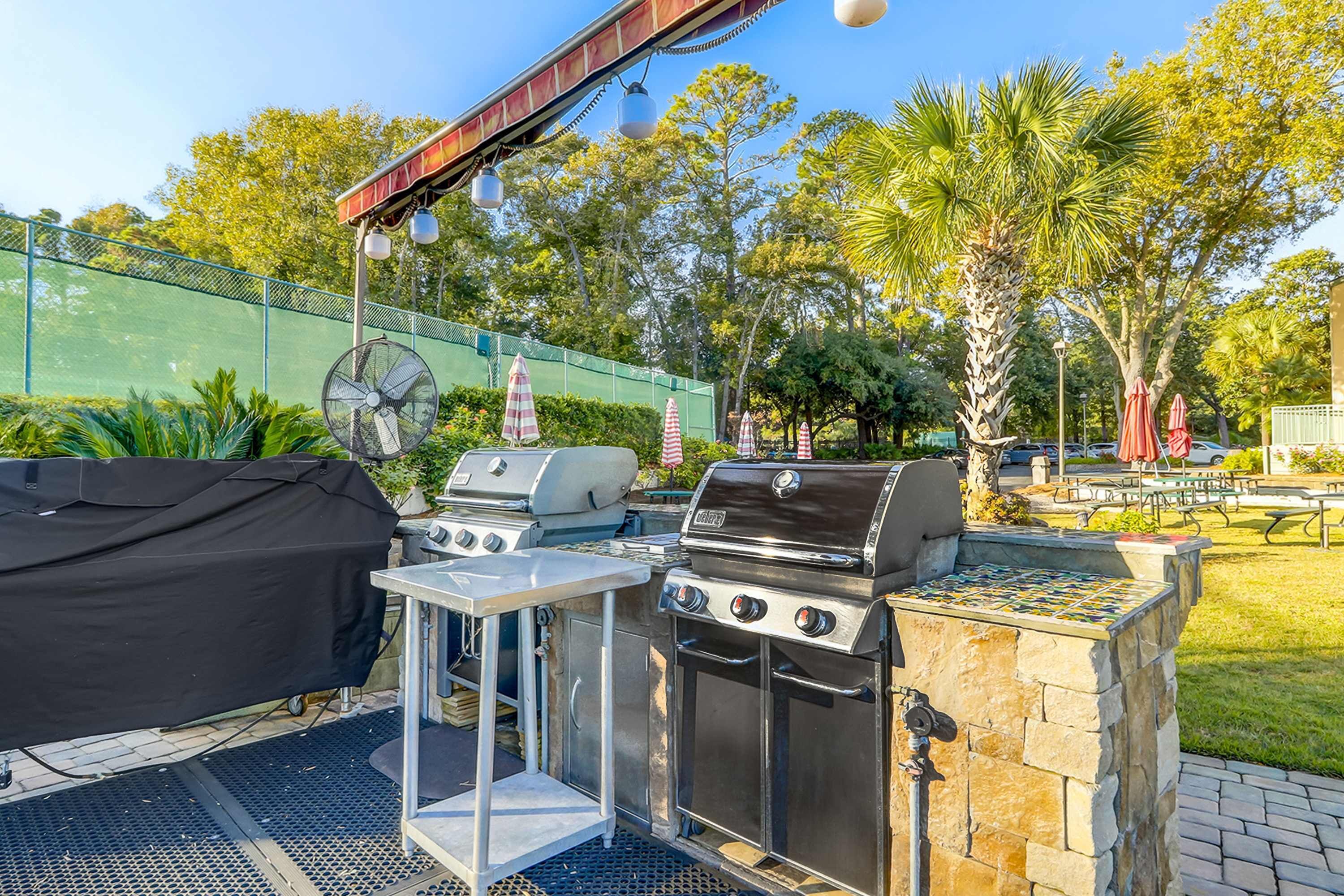 An outdoor grilling area with a covered grill, a fan, and a stone barbecue station.