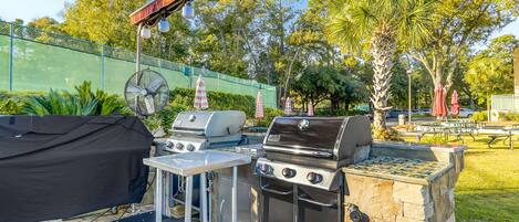 An outdoor grilling area with a covered grill, a fan, and a stone barbecue station.