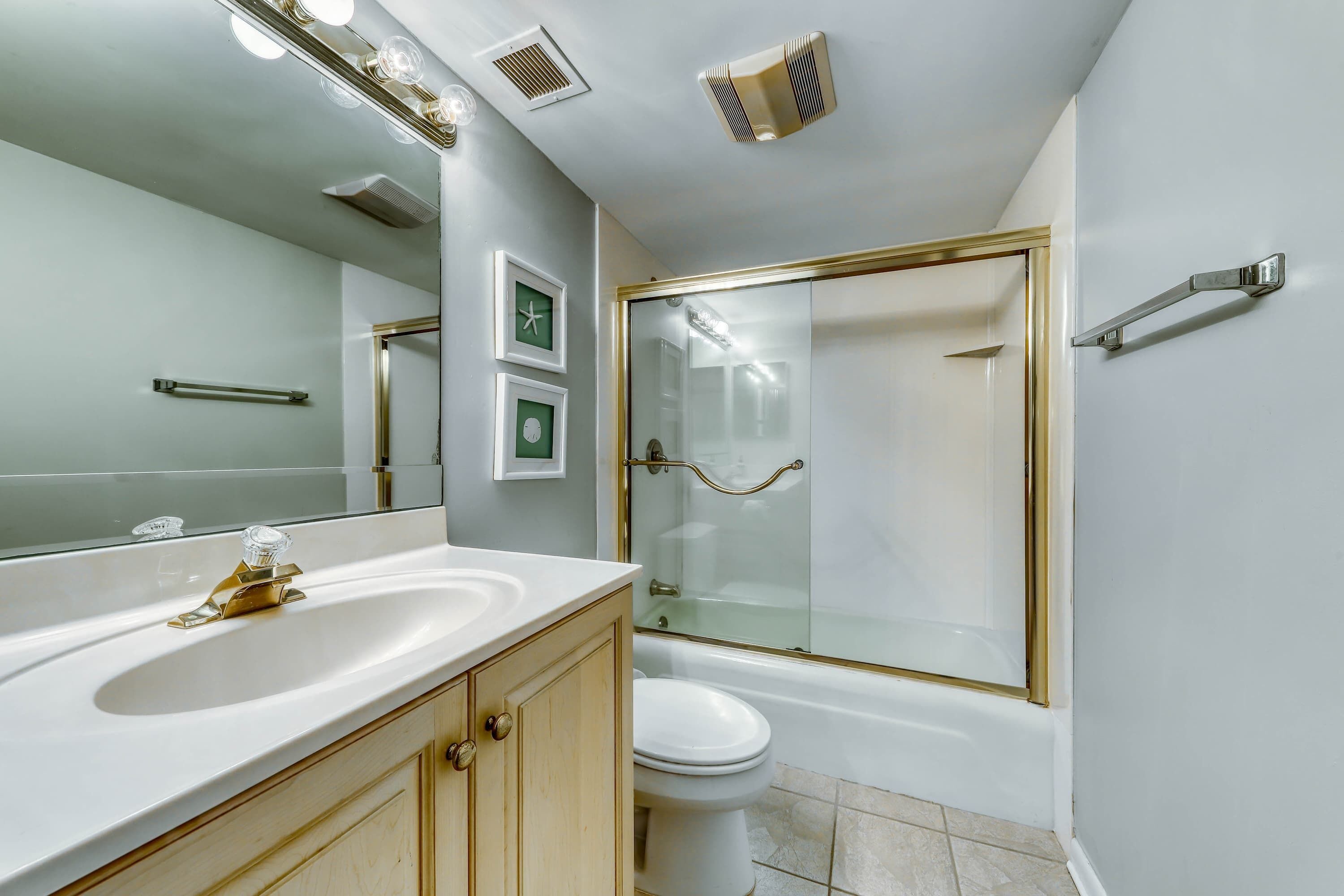 A bathroom with a white sink, a toilet, a glass-enclosed shower, and a large mirror.