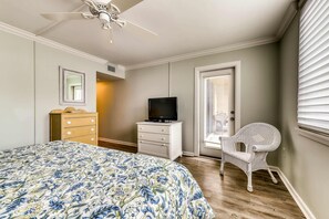 A bedroom with a bed, a television on a dresser, a chair, and a ceiling fan. - Modern Condo with Shared Pool and Hot Tub, Lagoon View, and Nearby Beach Access (Hilton Head)