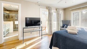 Una camera da letto con un letto, una TV su un mobile, una ventola a soffitto e vista all'esterno da una finestra.