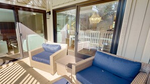 Zona relax esterna riparata, con mobili in vimini e cuscino blu.