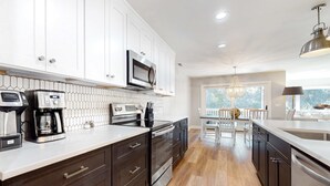 Una cucina moderna con mobili bianchi, elettrodomestici in acciaio inossidabile e pavimento in legno.