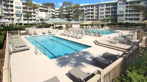 Un hotel con piscina, tumbonas y una zona de patio cubierta.