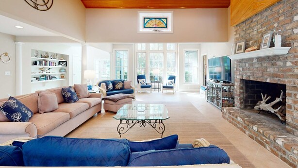 A spacious living room with a fireplace, a ceiling fan, and a bookshelf. - Spacious Home with Private Pool, Game Room, & Big Backyard - Great for Groups (Hilton Head)