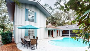 A modern house with a swimming pool, a patio with outdoor furniture, and a covered area with sliding glass doors. - Spacious Home with Private Pool, Game Room, & Big Backyard - Great for Groups (Hilton Head)