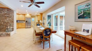 A spacious kitchen with a dining area, a ceiling fan, and a framed picture of a bird. - Spacious Home with Private Pool, Game Room, & Big Backyard - Great for Groups (Hilton Head)