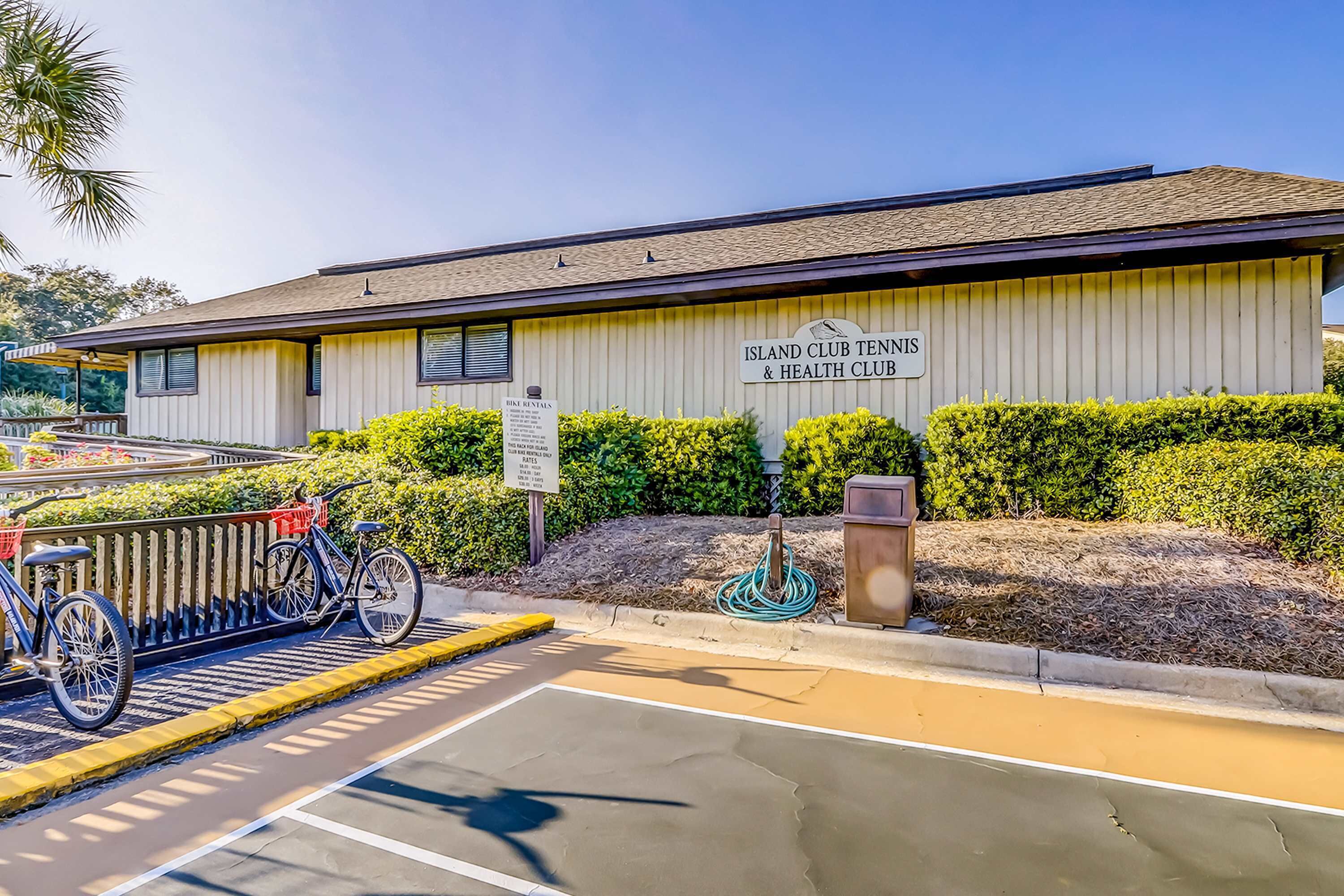 Un bâtiment sur lequel on peut lire l’inscription « Island Club Tennis & Health Club », un vélo garé à l’extérieur et un ciel dégagé.