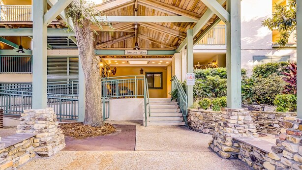 A building entrance with a 'Welcome Home' sign, a staircase, and a stone wall. - Updated Condo with Lagoon Views, Shared Pool, Hot Tub & WiFI - Near Beach (Hilton Head)