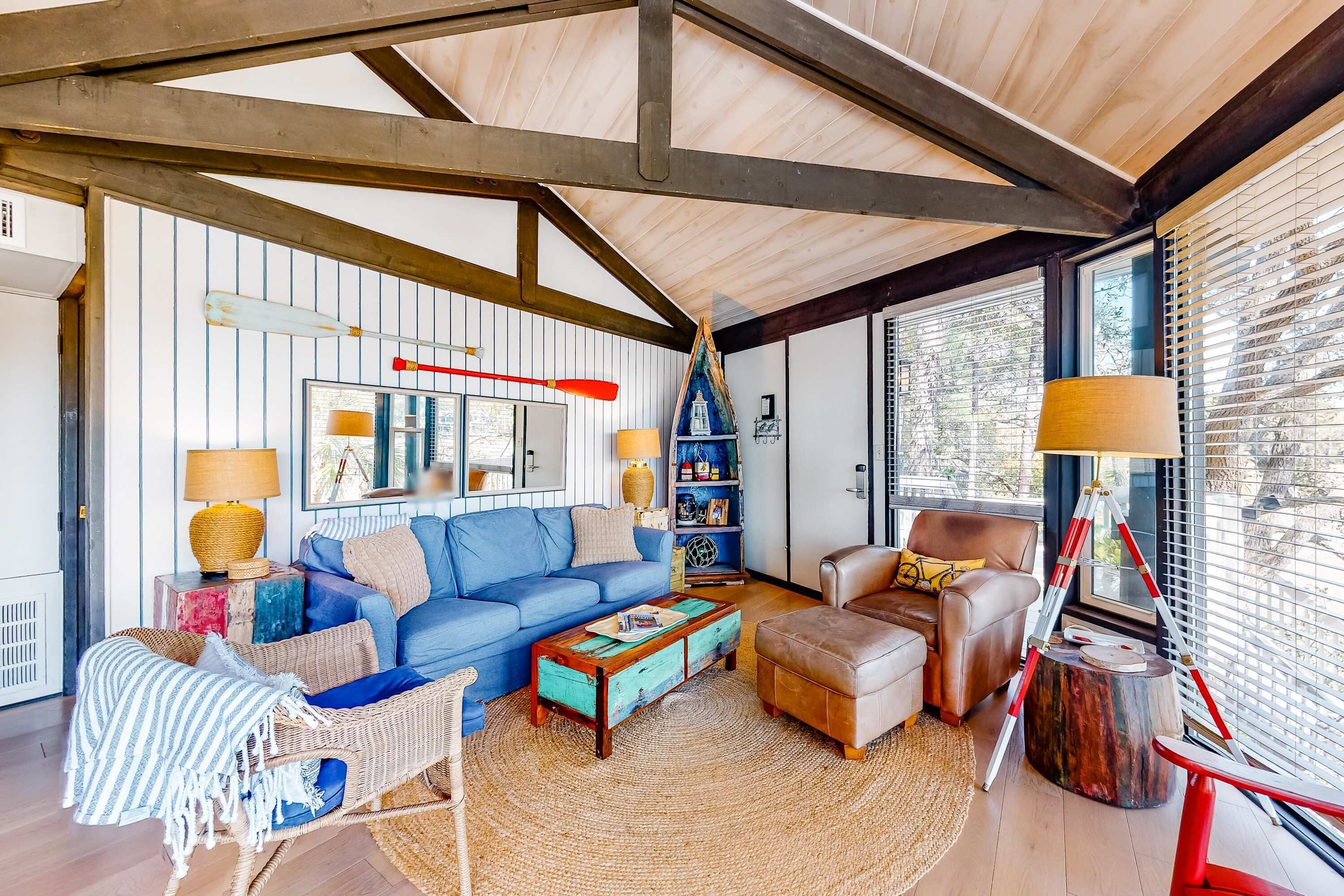 Un salon chaleureux avec un canapé bleu, une table basse, un fauteuil en osier et une échelle en bois.