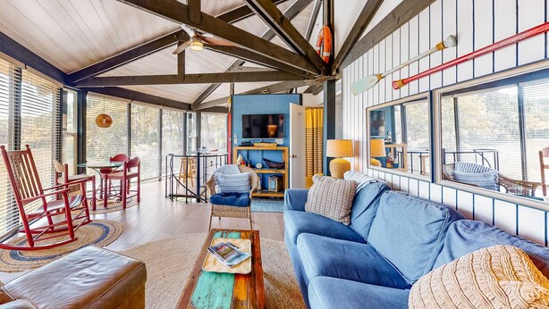 A spacious living area with a blue sofa, wooden coffee table, and a rocking chair. - Unique Treehouse Haven with Marsh-Front Views & Large Deck - Walk to Harbour Town (Hilton Head)