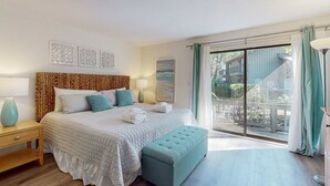 Un dormitorio con una cama grande, un banco, una mesita de noche y vistas al exterior.