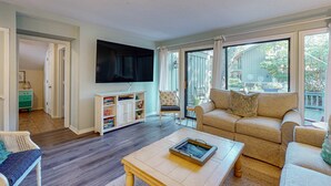 Una sala de estar con televisor, sofá, mesa de centro y estantería.