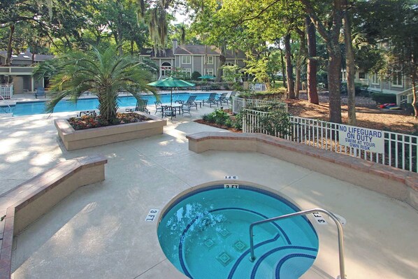 A pool area with a lifeguard duty sign, lounge chairs, and a palm tree. - Spacious Condo with Shared Pool, Tennis, Golf & Beach Access (Hilton Head)