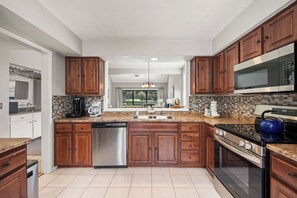 A modern kitchen with wooden cabinets, a stainless steel dishwasher, a built-in oven, and a microwave. - Spacious Condo with Shared Pool, Tennis, Golf & Beach Access (Hilton Head)